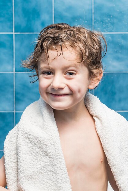 Foto retrato de un niño sonriente contra una pared de azulejos