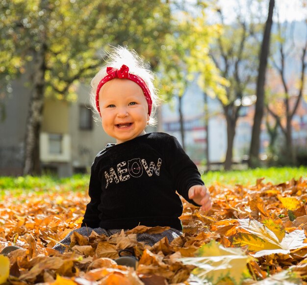 Foto retrato de un niño sonriente con hojas durante el otoño