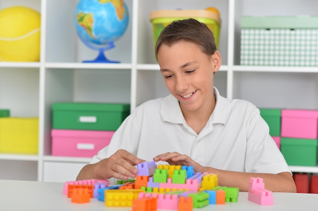 Foto retrato de niño sonriente jugando con coloridos bloques de plástico