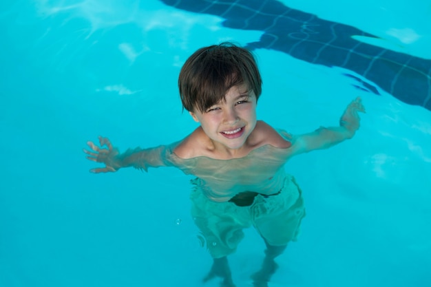 Retrato de niño sonriente nadando en la piscina del centro de ocio