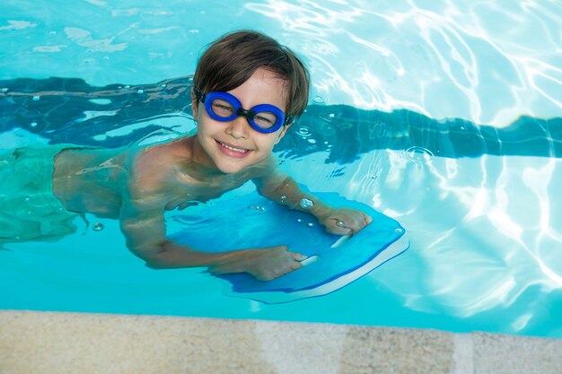 Retrato de niño sonriente nadando en la piscina del centro de ocio