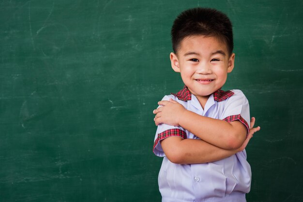 Foto retrato de un niño sonriente de pie contra la pared