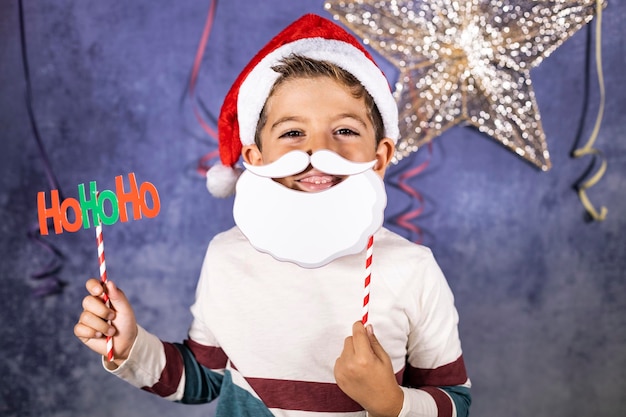 Foto retrato de un niño sonriente sosteniendo una decoración mientras está de pie contra la pared