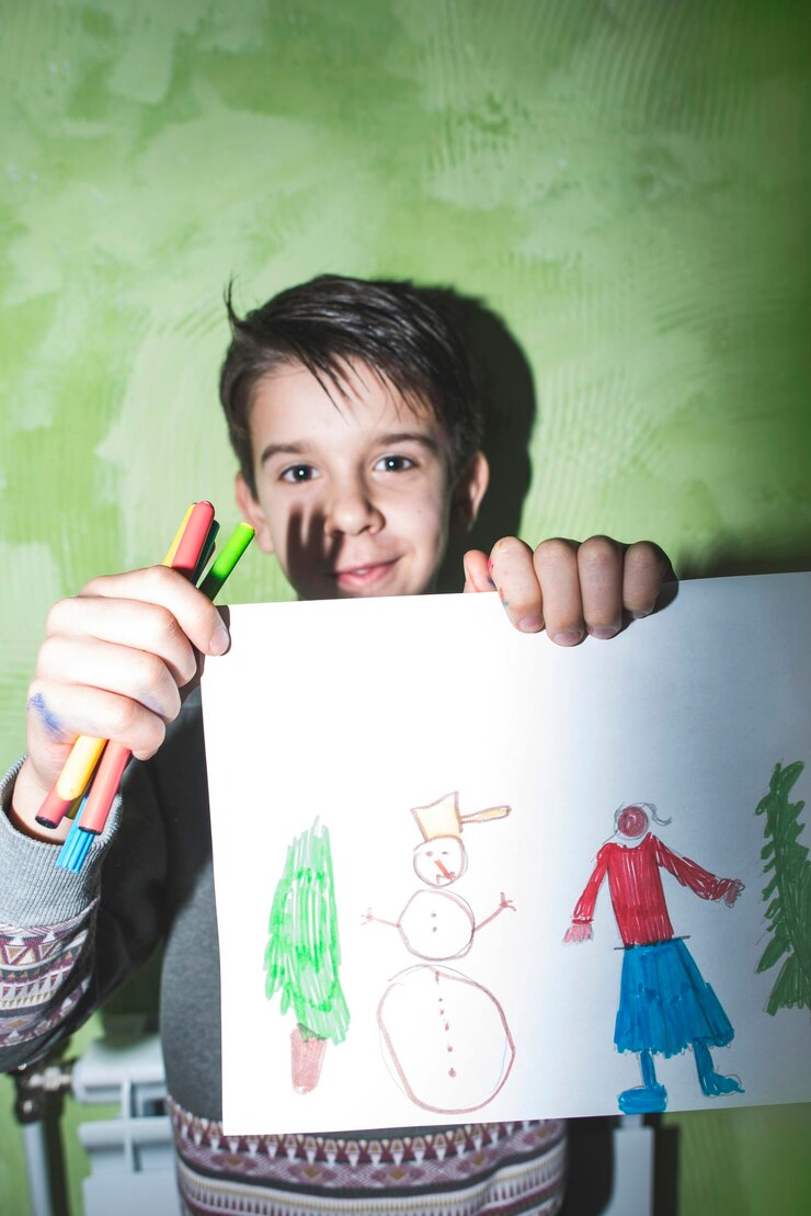 Foto retrato de un niño sonriente sosteniendo una pintura contra la pared