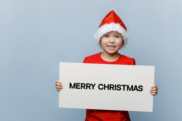 Retrato de un niño sonriente sosteniendo un sombrero contra un fondo blanco