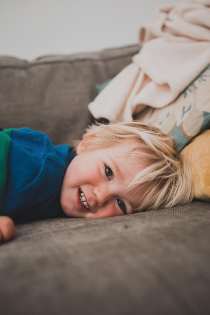 Retrato de un niño sonriente tendido en el sofá en casa