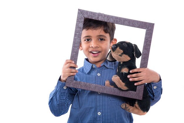 Retrato de un niño sosteniendo una mascota de peluche con marco sobre un fondo blanco.