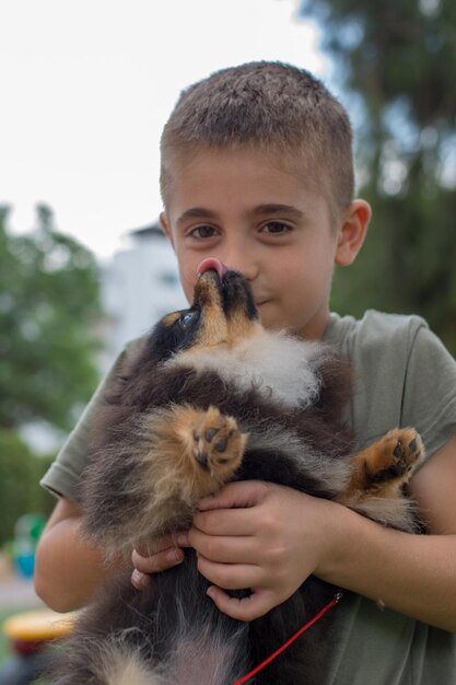 Foto retrato de un niño sosteniendo un perro mientras está de pie al aire libre