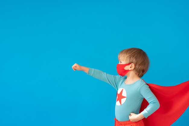 Retrato de niño superhéroe contra la pared de papel azul.