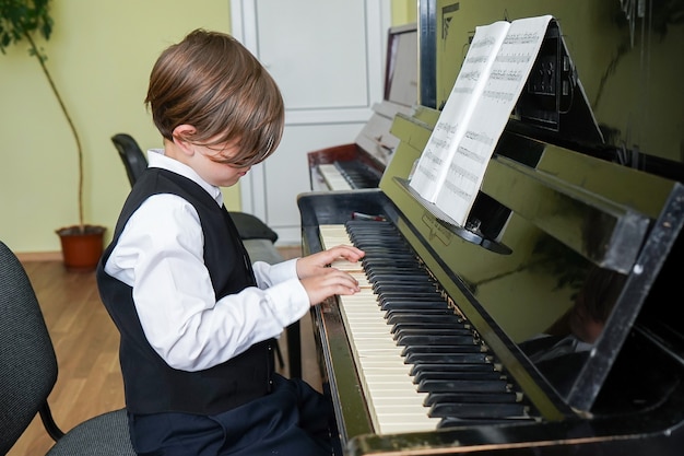 Foto retrato de niño tocando el piano, joven aprendiendo música con un piano en musical scholl. niño, relajante, tocar el piano