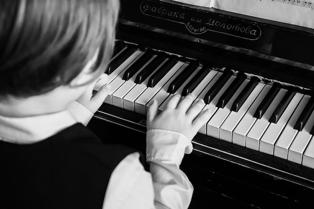 Retrato de niño tocando el piano, joven aprendiendo música con un piano en musical scholl. Niño, relajante, tocar el piano