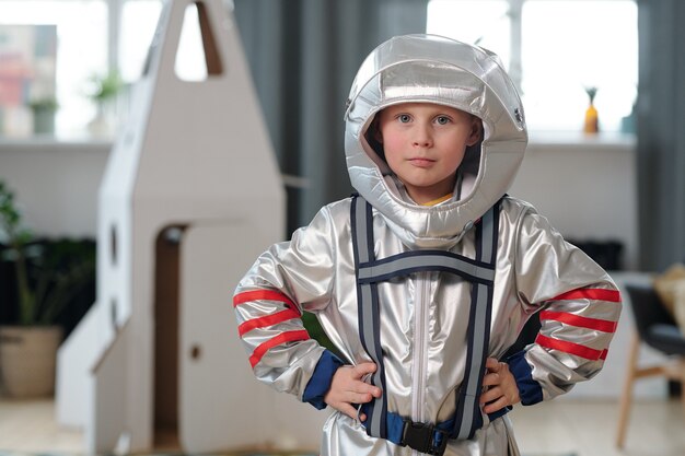 Retrato de niño en traje de astronauta mirando a la cámara mientras juega en casa