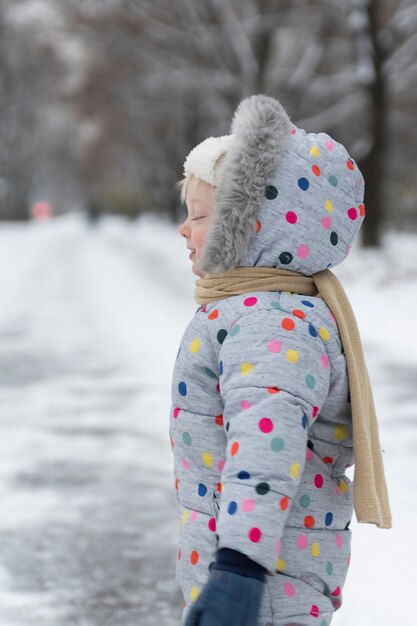 Retrato de niño en traje de nieve de invierno para caminar en el parque. Marco vertical.