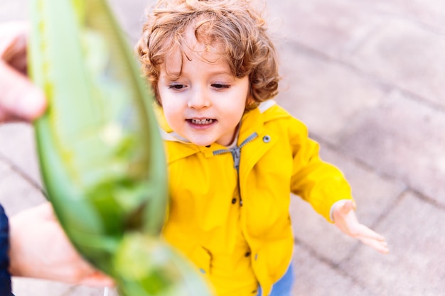 Retrato de niño de tres años jugando en primavera con un globo en la calle de la ciudad