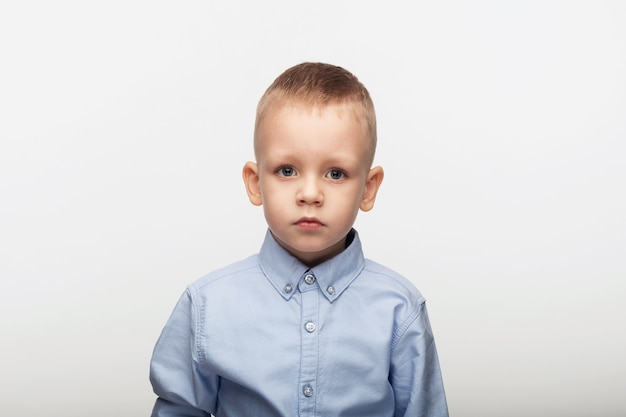 Retrato de un niño triste con una camisa azul