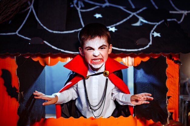 Retrato de un niño vestido con un traje de vampiro sobre fondo grunge. Fiesta de Halloween.