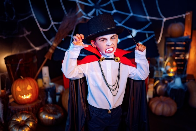 Retrato de un niño vestido con un traje de vampiro y sombrero sobre fondo grunge. Fiesta de Halloween.