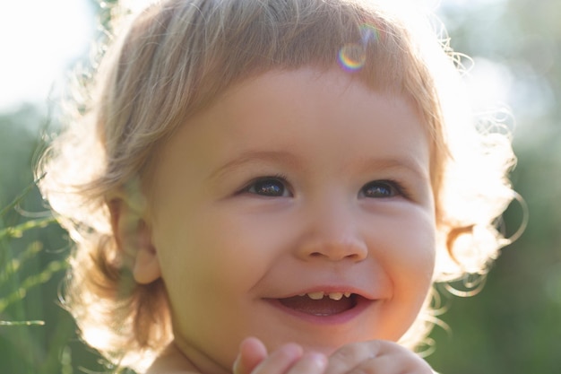 Retrato de niños, cierre la cabeza de un niño lindo. Bebé sonriendo, linda sonrisa en un día soleado. Cara recortada al aire libre.