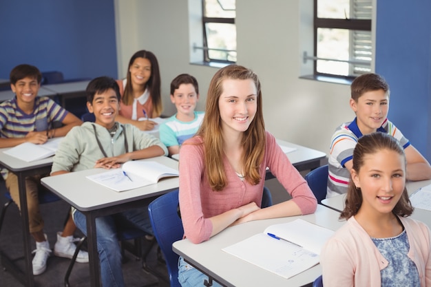 Foto retrato de niños de la escuela sonriente sentado en el aula