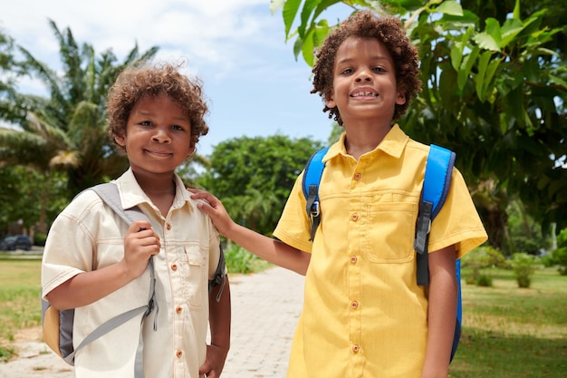 Retrato de niños felices con mochilas caminando en un parque soleado