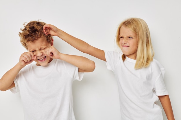 Retrato de niños lindos en camisetas blancas están de pie junto a la infancia sin cambios