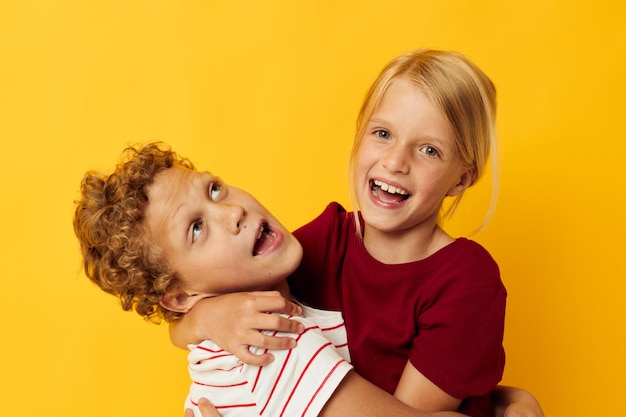 Retrato de niños lindos de pie uno al lado del otro posando emociones infantiles fondo amarillo