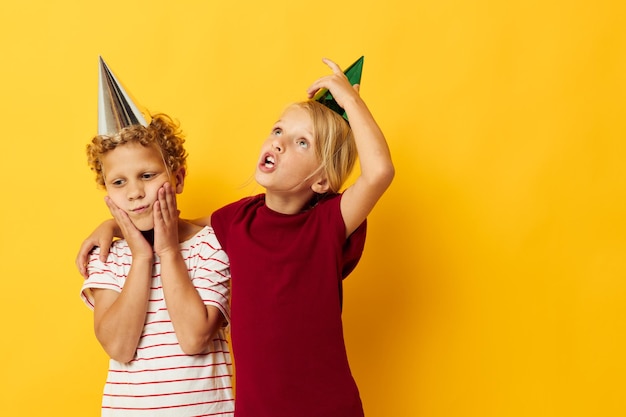 Retrato de niños lindos en ropa casual con gorras en la cabeza sobre fondo de color