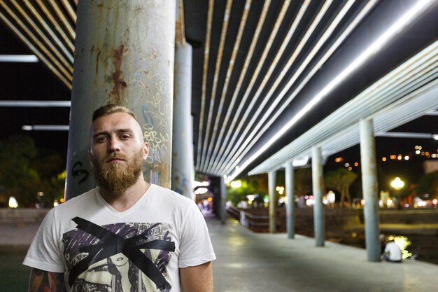 Foto retrato nocturno de un hombre barbudo de la calle vendedor de drogas pandillero bandido