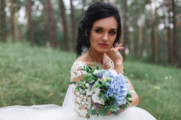 retrato noiva linda com um buquê de casamento delicado nas mãos ao ar livre em dia de sol