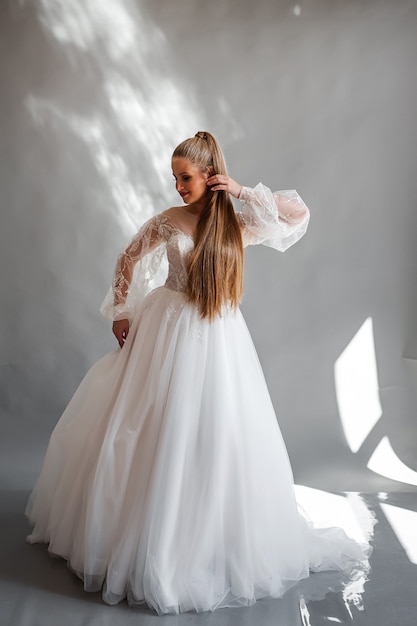 Retrato de novia perfecta de una niña con un vestido largo blanco Hermoso cabello y piel limpia y delicada