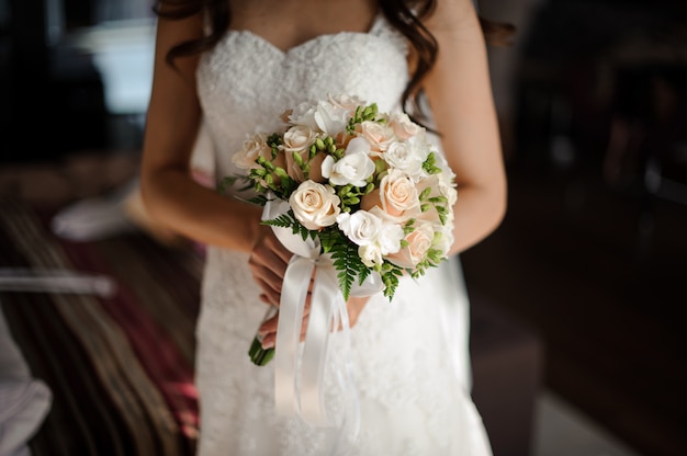 Retrato de novia en vestido de novia largo lujoso blanco, velo y ramo