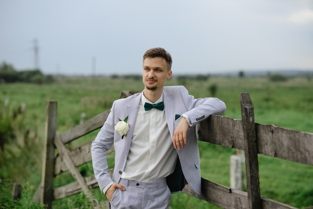 Retrato de un novio cerca de una valla de madera.