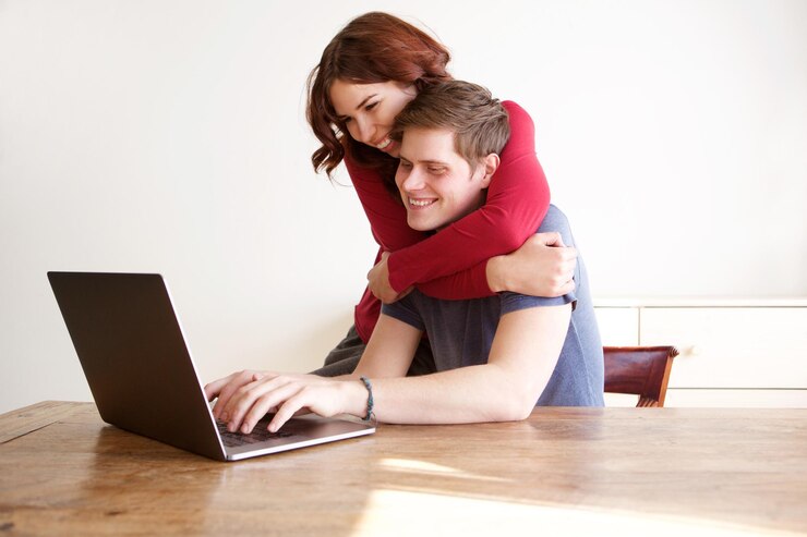 Foto retrato de novio y novia felices usando una computadora portátil en casa