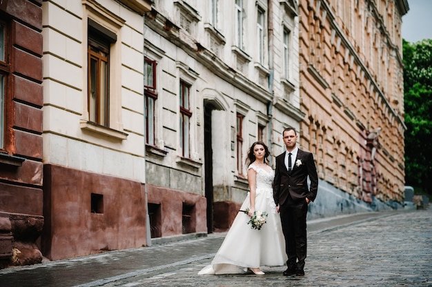 Retrato del novio y la novia de pie cerca del antiguo edificio al aire libre. Recién casados en las calles de la ciudad.