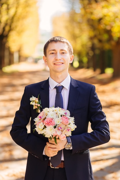 Retrato de un novio con ramo de boda en el parque otoño