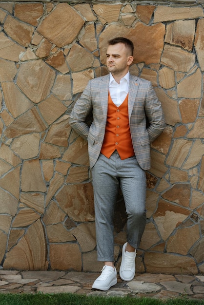 Retrato del novio con traje gris y chaleco naranja.