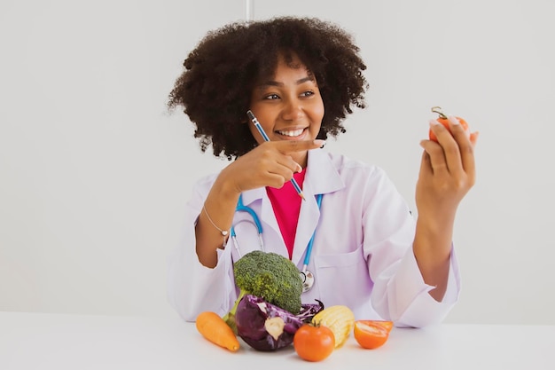 Retrato nutricionista feminina afro-americana olhando tomates saudáveis em um laboratório de hospital