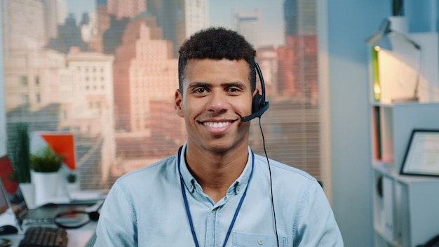 Retrato del operador de servicio al cliente de raza mixta en un auricular sonriendo a la cámara