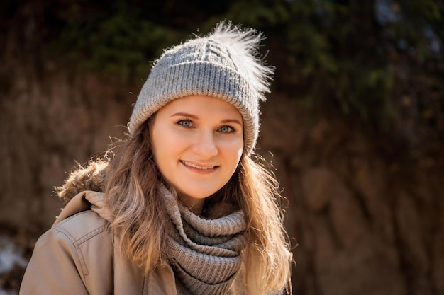 Retrato otoñal de mujer sonriente joven rubia caucásica en suéter gris y gorro al aire libre