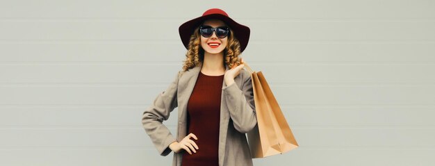 Retrato de otoño de una hermosa mujer joven con una bolsa de compras una chica elegante en abrigo sobre un fondo gris
