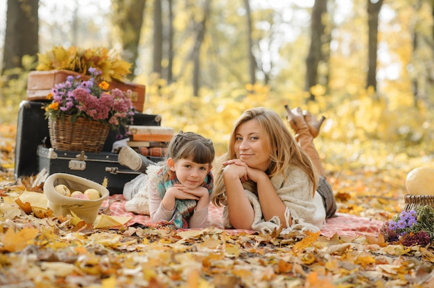 Retrato de otoño de mamá con una hija en el parque de otoño.