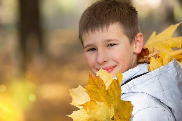 Retrato de otoño de un niño en hojas amarillas de otoño