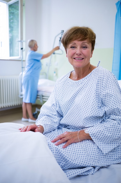 Retrato de paciente sonriente sentado en la cama