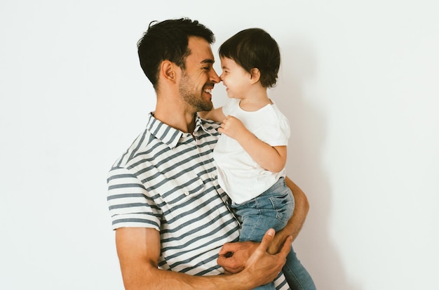 Retrato de padre e hija felices jugando y acurrucándose contra fondo blanco Buena relación entre padres e hijos Momentos familiares felices de padre y niña pequeña Infancia y paternidad