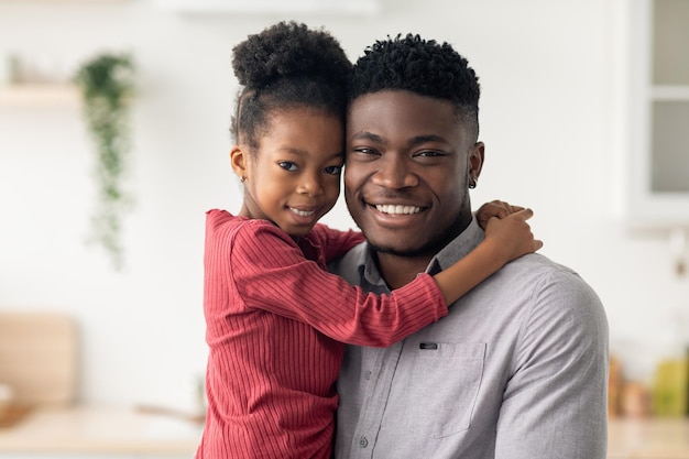 Retrato de padre e hija negros alegres sonriendo a la cámara