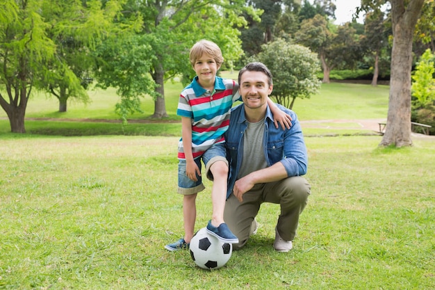 Retrato de padre e hijo con pelota en el parque