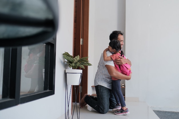 Retrato de padre feliz asiático dando la bienvenida a su hijo después de terminar la escuela