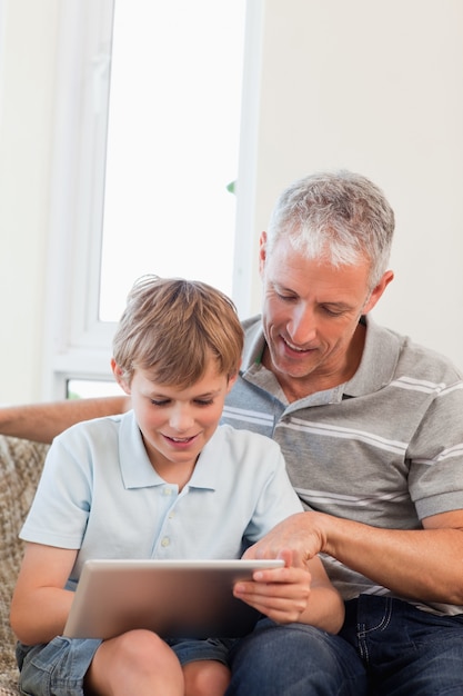 Retrato de un padre feliz y su hijo usando una tableta