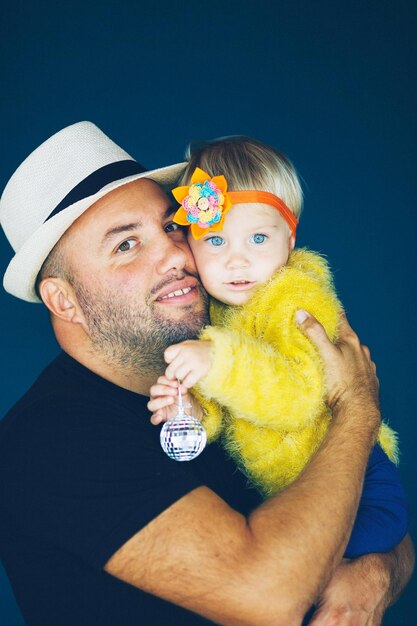 Foto retrato de un padre llevando a su hija contra un fondo azul