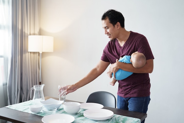 Retrato de padre soltero haciendo quehaceres domésticos mientras lleva a su bebé